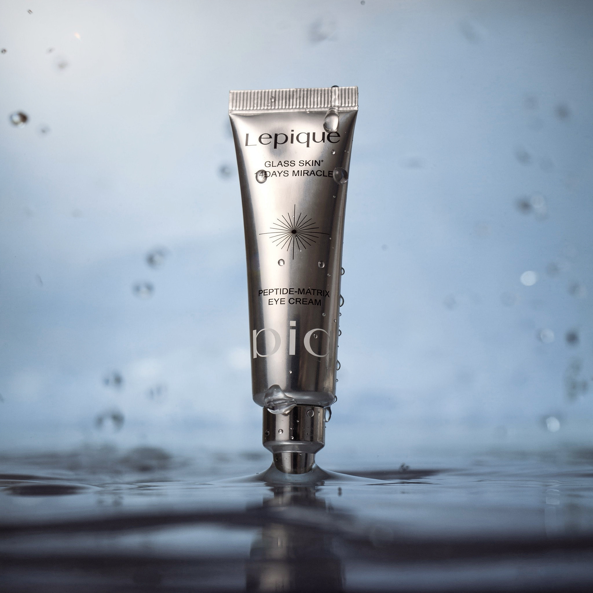 {
  "scene": "A product replacement edit where the perfume bottle from image 1 is swapped with the eye cream tube from image 2. The new product is placed in the center of the dark, atmospheric environ