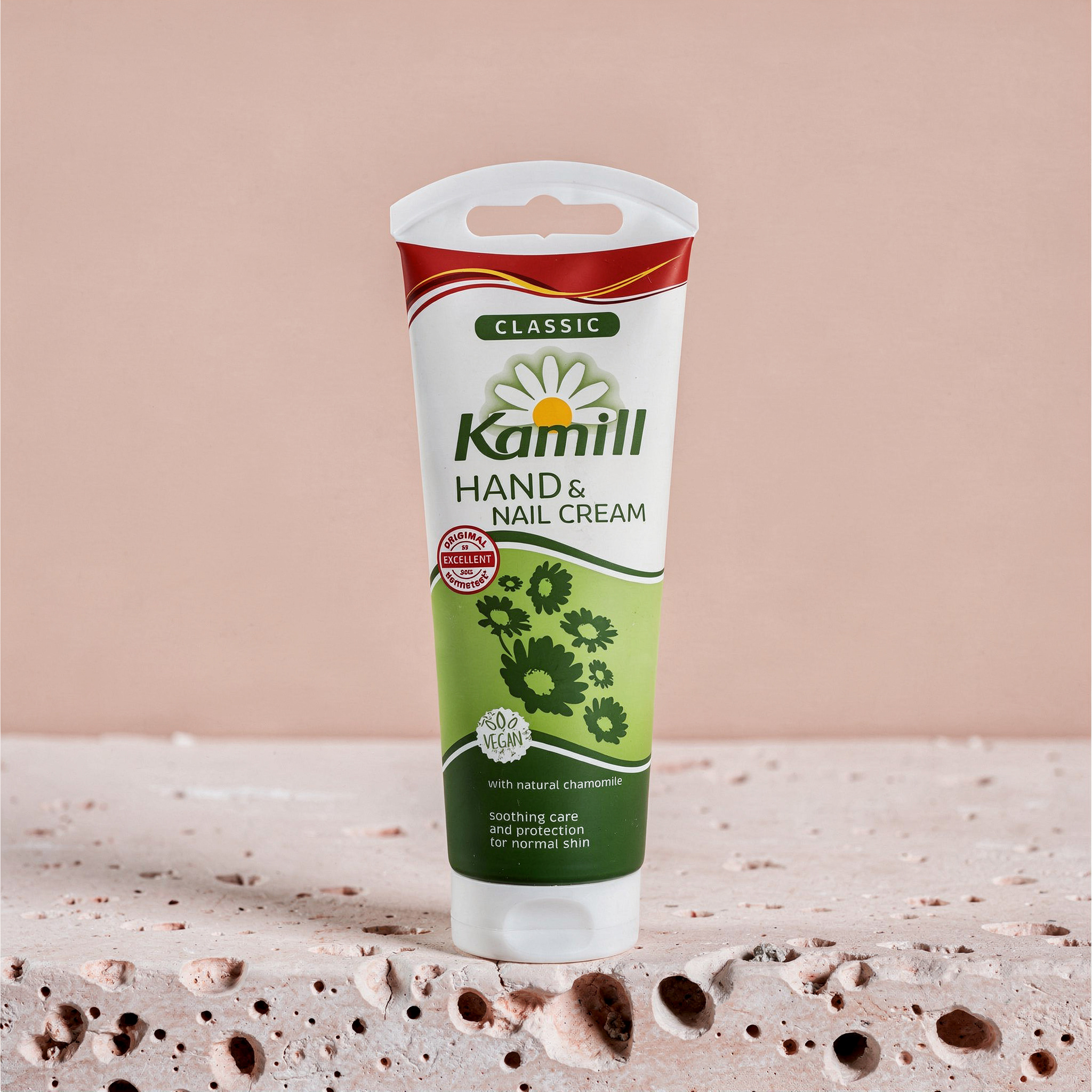 {
  "scene": "A minimalist studio product shot featuring the skincare product from image 2 placed perfectly centered in the setting from image 1. The background is a soft, solid pastel peach-pink wall