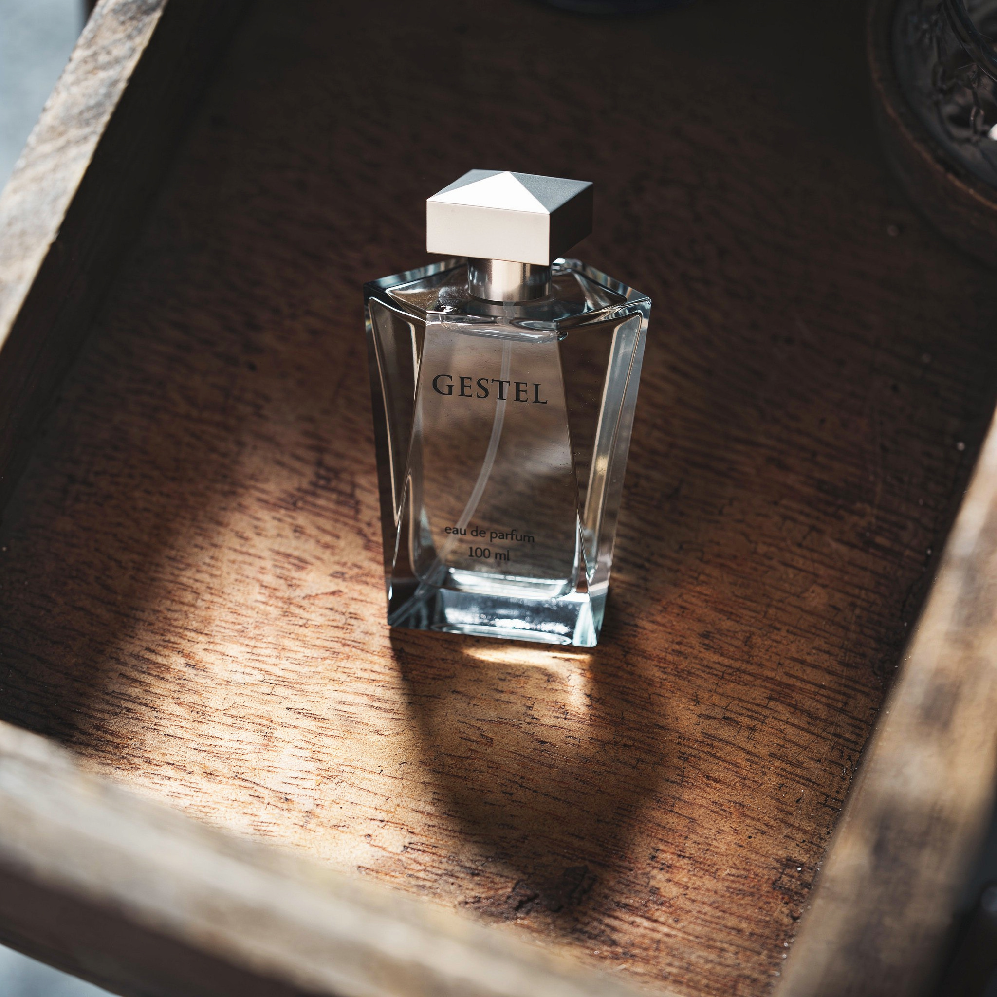 {
  "scene": "The luxury perfume bottle from image 2 is positioned within the rustic, weathered wooden drawer from image 1, replacing the original item while maintaining the exact environmental contex