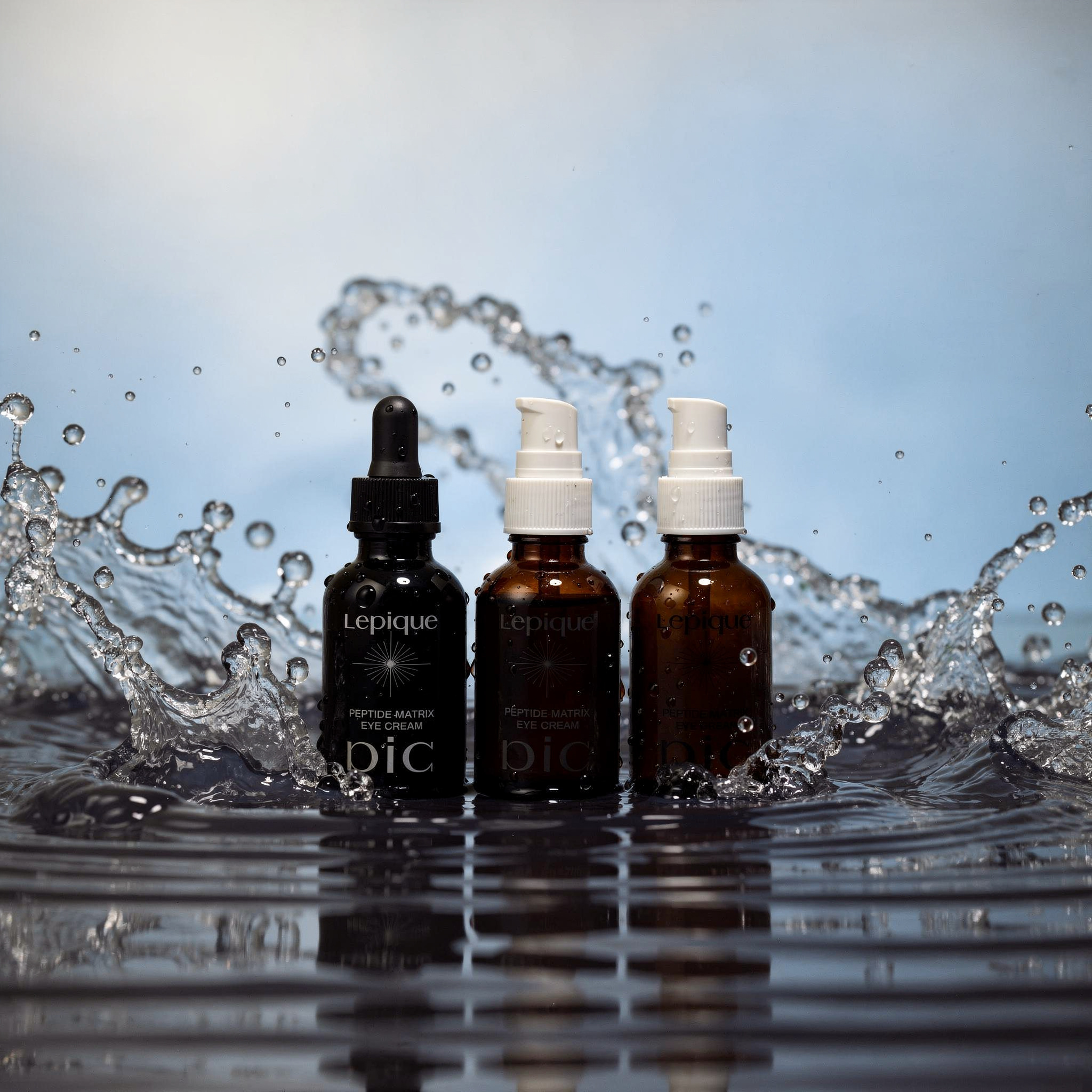 {
  "scene": "A professional product photography composition where the collection of apothecary bottles from image 2 is placed into the aquatic environment of image 1. The bottles are positioned centr